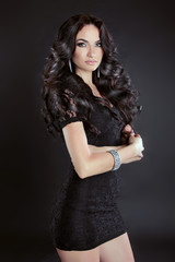 Fototapeta premium Brunette woman with long curly hair posing in dress, isolated on