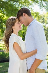 Obraz premium Cute couple hugging and smiling in the park