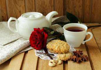 Still life with cup of tea, red rose and  oatmeal cookies.