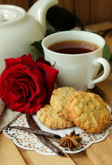 Still life with cup of tea, red rose and oatmeal cookies.