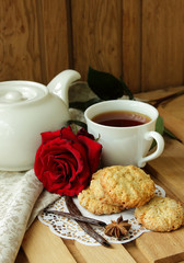 Still life with cup of tea, red rose and  oatmeal cookies.