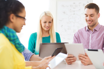 smiling team with table pc and laptop in office