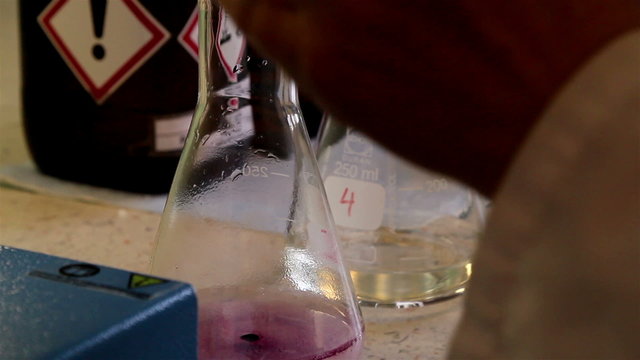 A laboratory technician putting chemicals in the flask