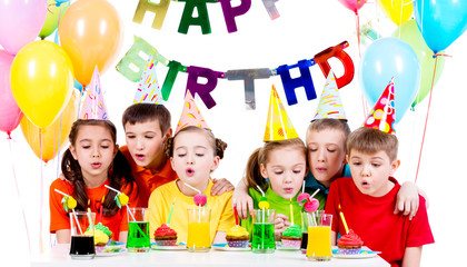 Group of kids blowing candles at the birthday party.