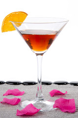 Cocktail glass with sunglasses, a flower petals and  black pebbl