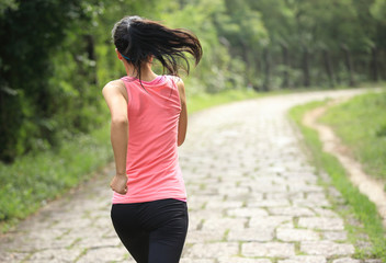 woman runner athlete running on forest trail