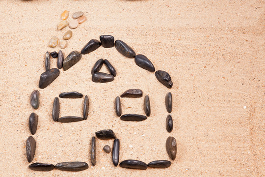 home designed with pebbles on the sand of a beach