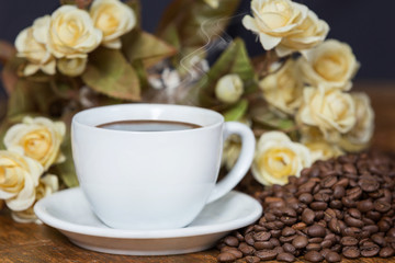 Beautifully arranged cup of coffee among beans and flowers.