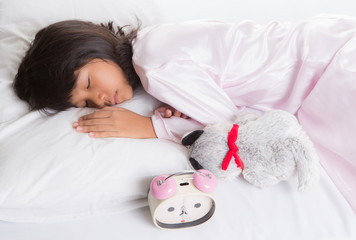 Young Asian Malay girl sleeping with alarm clock on her side