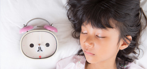 Young Asian Malay girl sleeping with alarm clock on her side