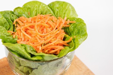 Lettuce and carrot salad in glass bowl.