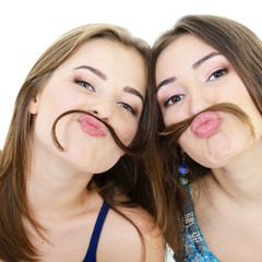 Portrait of a two teen girls have fun and make faces with mousta