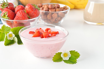 Delicious strawberry yogurt on white table.
