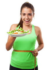young sporty woman measuring herself and holding a salad on whit