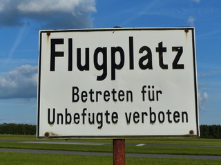 Hinweisschild mit Warnung vor blauem Himmel mit weißer Wolke im Sommer am Segelflugplatz in...