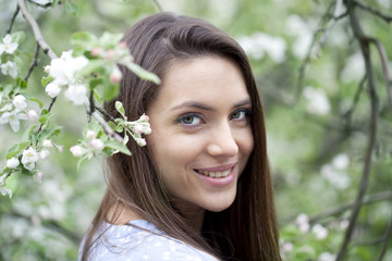 Beautiful woman standing near blooming trees in spring garden