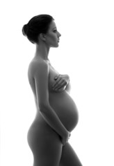 Naked pregnant woman with a beautiful belly on white