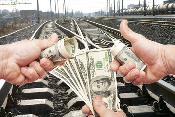 Hands with notes of dollars against the railroad