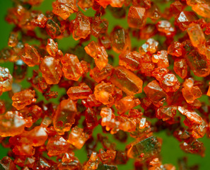 Orange crystals on a green background. Extreme closeup. Macro