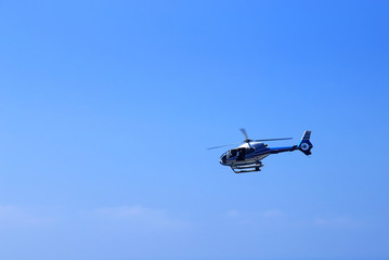 Fototapeta na wymiar Helicopter flying against the blue background sky