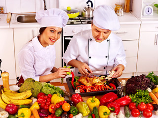 Man and woman in chef hat cooking chicken
