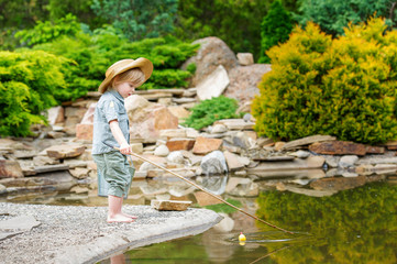 Cute child fishing by the pond in the beautiful garden