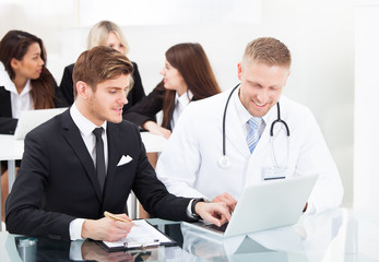 Doctor And Businessman Discussing Over Laptop