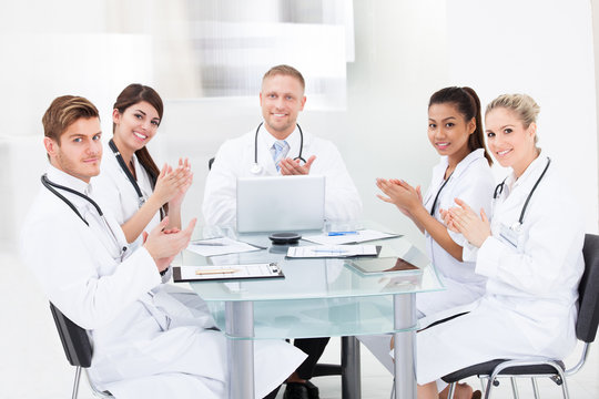 Confident Doctors Applauding At Desk