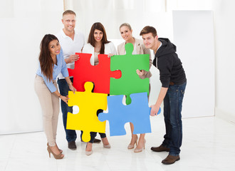 Confident Businesspeople Joining Puzzle Pieces