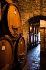 Antique wine cellar with row of big barrels full of wine