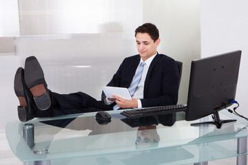 Relaxed Businessman Using Digital Tablet In Office