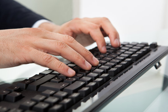 Businessman Using Computer Keyboard At Desk