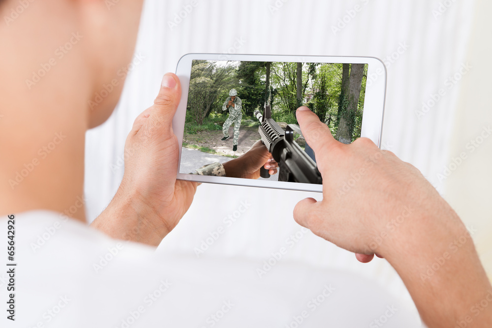 Poster man playing action game on digital tablet at home