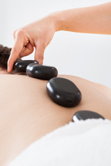 Therapist Placing hot stones On Man's Back In Spa