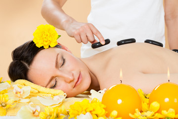 Woman Receiving Hot Stone Therapy In Spa