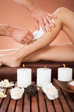 Therapist Waxing Customer's Leg At Beauty Spa