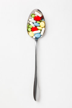 Many colorful pills and tablets in spoon.