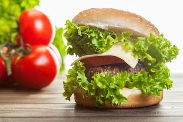 Cheeseburger with lettuce, onions and tomato in a sesame bun
