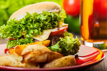 Cheeseburger with fried potatoes on a plate with beer