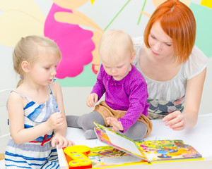 Fototapeta premium Mother and her daughters reading a book.