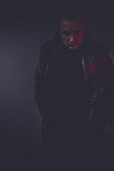 shadow portrait of stylish man with long leather jacket, gun arm