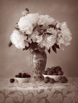 Ripe cherries and strawberries with bouquet of peonies
