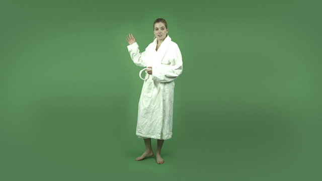 attractive caucasian girl in bathrobe isolated on green talking