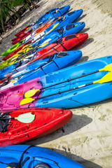 colorful kayaks lined in a row on a white sand beach