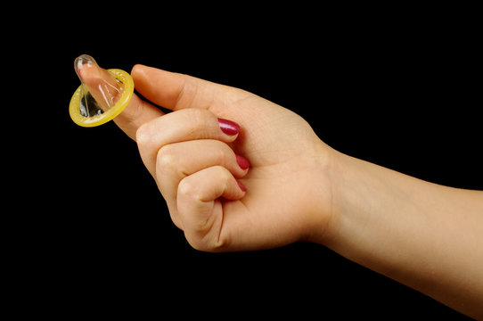 Hand holding wrapped condom on the black background