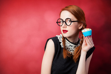 Redhead girl with cupcake on red background