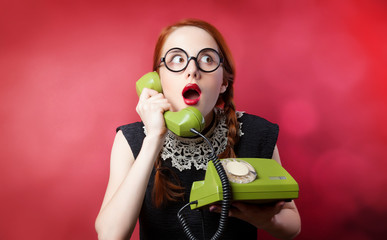 Redhead girl with green phone on red background.