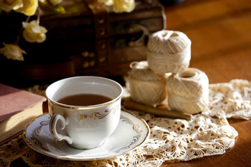 Tea cup and crochet lace on wooden table.
