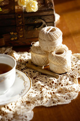 Tea cup and crochet lace on wooden table.