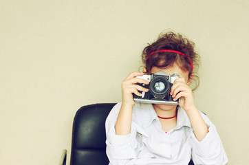 Cheerful kid holding old camera. retro filter room for text. 